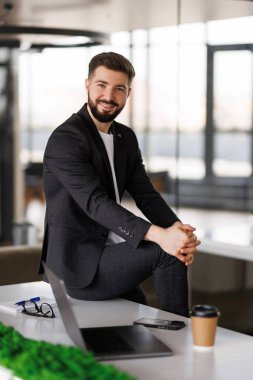 Ofisteki masasında oturan genç adamın portresi.