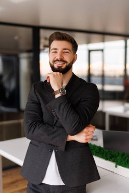 Kendine güvenen ciddi bir iş adamı, düşünceli şirket CEO 'su mavi takım elbiseli, ofiste el ele tutuşmuş kameraya bakıyor düşünüyor, karar veriyor, şüphe duyuyor..