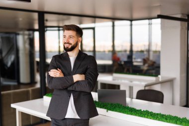 Resmi gömlekli, elleri katlı ve dişlek bir gülümsemeyle kameraya bakan yakışıklı bir yönetmen. Neşeli iş profesyoneli, yönetici, girişimci portresi