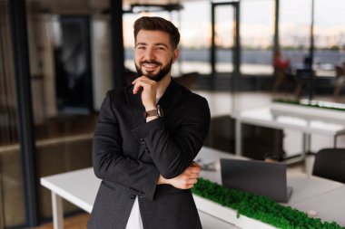 Kendine güvenen ciddi bir iş adamı, düşünceli şirket CEO 'su mavi takım elbiseli, ofiste el ele tutuşmuş kameraya bakıyor düşünüyor, karar veriyor, şüphe duyuyor..