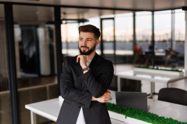 Kendine güvenen ciddi bir iş adamı, düşünceli şirket CEO 'su mavi takım elbiseli, ofiste el ele tutuşmuş kameraya bakıyor düşünüyor, karar veriyor, şüphe duyuyor..
