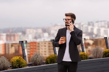 Bir duraklama almak. Bel kadar telefonla konuştuktan sonra office balkonda kahve içme gülümseyen işadamı portresi. Kopya alanı sağ