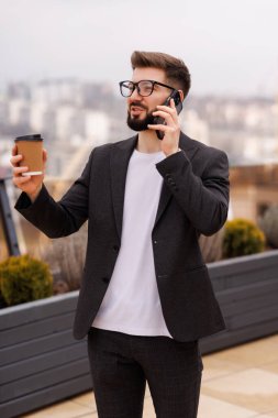 Bir duraklama almak. Bel kadar telefonla konuştuktan sonra office balkonda kahve içme gülümseyen işadamı portresi. Kopya alanı sağ