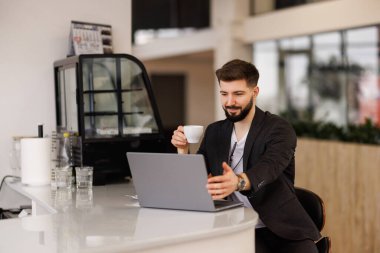 Diz üstü ofis video izlerken kahve içme gözlük yakışıklı işçi gülümseyen