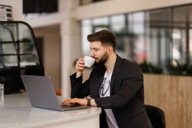 Diz üstü ofis video izlerken kahve içme gözlük yakışıklı işçi gülümseyen