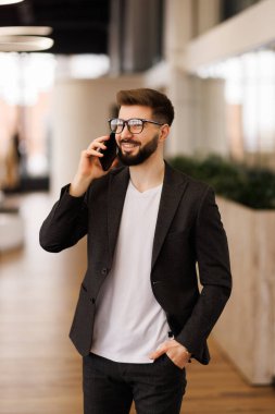 Yakışıklı iş Ceo ile tasarımcı anız güvenle üst kat ofis City büyük pencereler dışarı bakarken onun cep telefonu üzerinde konuşurken,