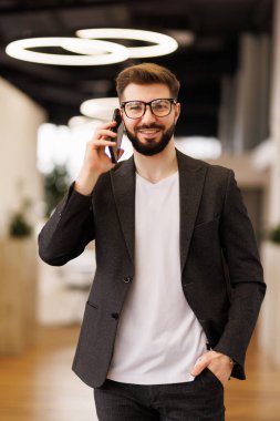 Yakışıklı iş Ceo ile tasarımcı anız güvenle üst kat ofis City büyük pencereler dışarı bakarken onun cep telefonu üzerinde konuşurken,