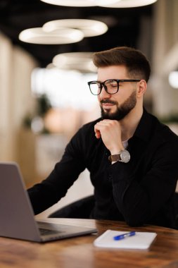 Evrak işleriyle uğraşan olgun bir işadamı, belgelerle, sözleşmelerle ve faturalarla uğraşan bir adam iş yerinde dizüstü bilgisayarını kullanan, sakallı ve gözlüklü bir muhasebeci..