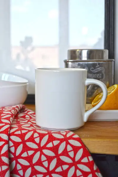 Kırmızı peçetede beyaz kupa, çay kabı ve limon dilimi.