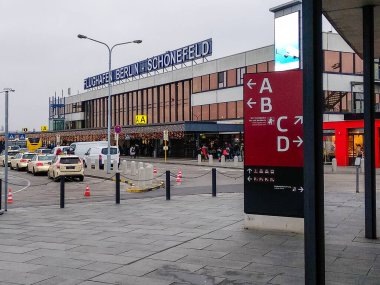 Berlin Schoenefeld Havaalanı 'nın dış cephesinde görünür taksiler, otobüsler, yolcular ve ön girişler için tabelalar bulunmaktadır..