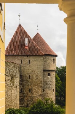 Tallinn Eski Kasabası 'nın güzel manzarası. Neoklasik bir binanın sarı sütunları çerçeveli ortaçağ taş kuleleri. Estonya mimari kontrastı ve mirası sergileniyor..