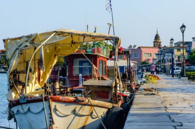 Yunanistan 'ın Zakynthos kentindeki liman boyunca eski balıkçı tekneleri demirlemiş durumda. Geleneksel renkler, balık ağları ve Saint Dionysios 'un çan kulesi nostaljik bir ada havası yaratır..