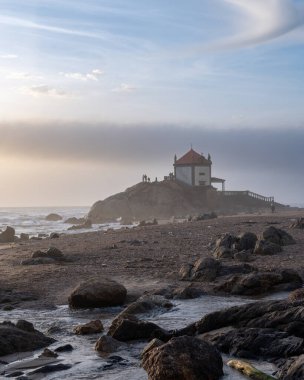 Sahildeki deniz feneri, kayalara vuran deniz dalgaları..