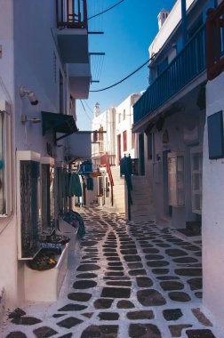 Kiklad Yunan adası Mykonos 'un eşsiz mimarisi, mavi pencereli klasik beyaz evler tarafından temsil ediliyor. Sokaklar çiçek açan ağaçlarda gömülü. Yunanistan 'ın en lüks tatil köyü. Yunan Adası Mykonos Sokağı