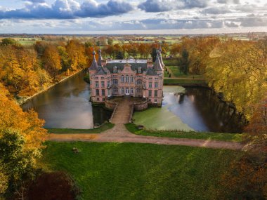 Parktaki şato sarı ağaçlarla çevrili, Belçika şatosu sonbahar manzaralı.