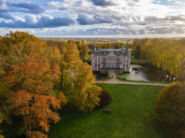 Parktaki şato sarı ağaçlarla çevrili, Belçika şatosu sonbahar manzaralı.