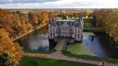 Parktaki şato sarı ağaçlarla çevrili, Belçika şatosu sonbahar manzaralı.