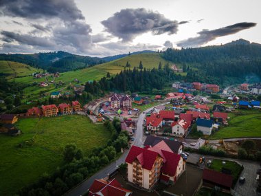Gün batımında dağlık kırsal bir manzara. Uzak vadinin üstündeki dramatik gökyüzü. Tepedeki yeşil tarlalar ve ağaçlar. Karpatların güzel doğa manzarası. Yüksek kalite fotoğraf