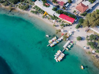 Chania, Girit 'teki doğal Kournas Gölü' nün çarpıcı hava aracı görüntüsü. Turkuaz sular etrafındaki tepeleri yansıtırken, beyaz pedallı tekneler huzur içinde göl yüzeyinde yüzüyor.