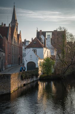 Bruges, Belçika - 8 Mart 2025 İnsanlar büyüleyici sokaklarında yürürken Bruges 'ün tarihi merkezi canlanıyor. Bu ortaçağ şehrinin özünü yansıtan canlı bir sahne..