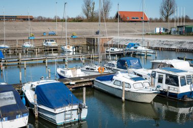 Hollanda 'nın Zeeland kentindeki sevimli bir köyün sessiz bir marinasına birkaç küçük tekne yanaştı. Sakin sular ve güzel manzaralar barışçıl ve davetkar bir atmosfer yaratır..