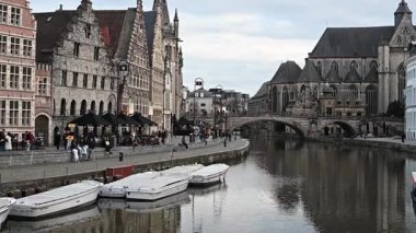 Gent, Belçika - 23 Mart 2025: Gent, Belçika 'da, büyüleyici tarihi mimari ve sudaki yansımalarla çevrili, kanallar boyunca yürüyen insanları gösteren resimli bir video. Canlı ve büyüleyici bir şehir..