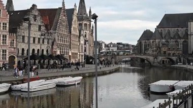 Gent, Belçika - 23 Mart 2025: Gent, Belçika 'nın muhteşem tarihi mimarisi ve su üzerindeki yansımaları ile çevrili, kanallar boyunca yürüyen insanları gösteren resimli bir video.