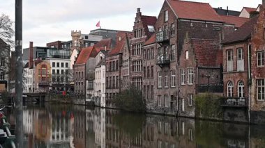 Gent, Belçika - 23 Mart 2025: Gent, Belçika 'nın muhteşem tarihi mimarisi ve su üzerindeki yansımaları ile çevrili, kanallar boyunca yürüyen insanları gösteren resimli bir video.