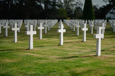Colleville-sur-Mer, Fransa - 9 Nisan 2025: Omaha Sahili yakınlarındaki Colleville-sur-Mer 'deki Amerikan Mezarlığı' nın resmi manzarası. Beyaz haç sıraları manikürlü çitler arasında mükemmel bir hizada duruyor..