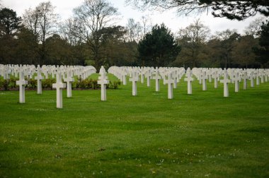 Colleville-sur-Mer, Fransa - 9 Nisan 2025: Omaha Sahili yakınlarındaki Colleville-sur-Mer 'deki Amerikan Mezarlığı' nın resmi manzarası. Beyaz haç sıraları manikürlü çitler arasında mükemmel bir hizada duruyor..
