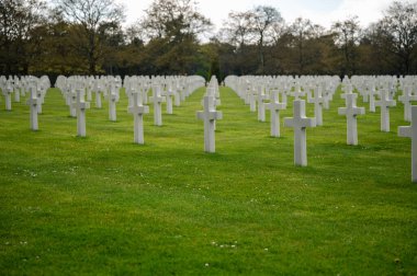 Colleville-sur-Mer, Fransa - 9 Nisan 2025: Omaha Sahili yakınlarındaki Colleville-sur-Mer 'deki Amerikan Mezarlığı' nın resmi manzarası. Beyaz haç sıraları manikürlü çitler arasında mükemmel bir hizada duruyor..