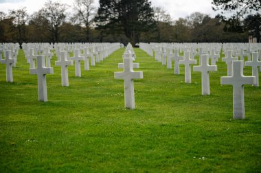 Colleville-sur-Mer, Fransa - 9 Nisan 2025: Omaha Sahili yakınlarındaki Colleville-sur-Mer 'deki Amerikan Mezarlığı' nın resmi manzarası. Beyaz haç sıraları manikürlü çitler arasında mükemmel bir hizada duruyor..