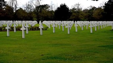 Colleville-sur-Mer, Fransa - 9 Nisan 2025: Omaha Sahili yakınlarındaki Colleville-sur-Mer 'deki Amerikan Mezarlığı' nın resmi manzarası. Beyaz haç sıraları manikürlü çitler arasında mükemmel bir hizada duruyor..