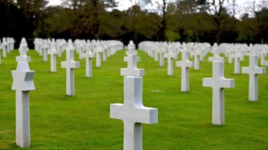 Colleville-sur-Mer, Fransa - 9 Nisan 2025: Omaha Sahili yakınlarındaki Colleville-sur-Mer 'deki Amerikan Mezarlığı' nın resmi manzarası. Beyaz haç sıraları manikürlü çitler arasında mükemmel bir hizada duruyor..