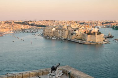 Birgu Limanı 'nın çarpıcı panoramik manzarası Valletta bakış açısından, tarihi mimari, kenetlenmiş tekneler ve manzaralı Malta kıyı şeridi sergileniyor..