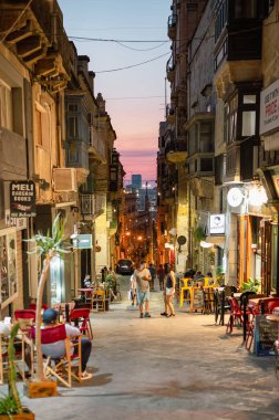 Valletta, Malta - 22 Temmuz 2022: Geleneksel mimari, renkli balkonlar ve eşsiz bir atmosferle dolu tarihi Valletta sokakları, ziyaretçileri güzelliğini keşfetmeye davet ediyor..