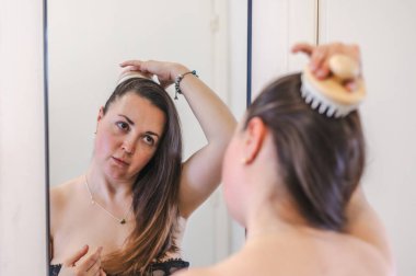 Bir kadın, günlük güzellik hizmetinin bir parçası olarak saçlarını nazikçe tarar. Sağlıklı, pürüzsüz ve bakımlı kilitleri teşvik eder..