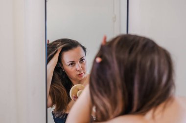 Bir kadın, günlük güzellik hizmetinin bir parçası olarak saçlarını nazikçe tarar. Sağlıklı, pürüzsüz ve bakımlı kilitleri teşvik eder..