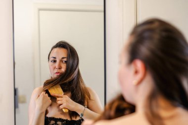 Bir kadın, günlük güzellik hizmetinin bir parçası olarak saçlarını nazikçe tarar. Sağlıklı, pürüzsüz ve bakımlı kilitleri teşvik eder..