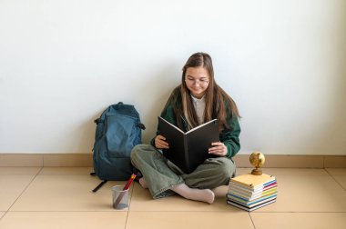 Elinde kitap tutan gülümseyen genç bir öğrenci, temiz beyaz bir arka plana karşı duruyor, okula ya da çalışmaya hazır..