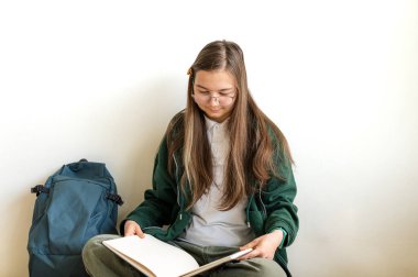 Elinde kitap tutan gülümseyen genç bir öğrenci, temiz beyaz bir arka plana karşı duruyor, okula ya da çalışmaya hazır..