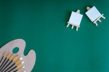 Yeşil bir arkaplanda düzenli olarak dizilmiş not defterleri, kalemler, keçeli kalemler ve makaslar da dahil olmak üzere okul malzemelerinden oluşan canlı bir çeşitlilik.