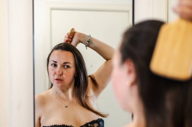 Bir kadın, günlük güzellik hizmetinin bir parçası olarak saçlarını nazikçe tarar. Sağlıklı, pürüzsüz ve bakımlı kilitleri teşvik eder..