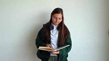 Elinde kitap tutan gülümseyen genç bir öğrenci, temiz beyaz bir arka plana karşı duruyor, okula ya da çalışmaya hazır..