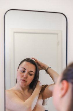 Bir kadın, günlük güzellik hizmetinin bir parçası olarak saçlarını nazikçe tarar. Sağlıklı, pürüzsüz ve bakımlı kilitleri teşvik eder..