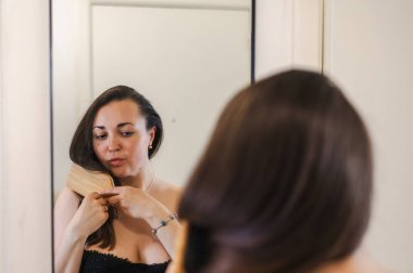 Bir kadın, günlük güzellik hizmetinin bir parçası olarak saçlarını nazikçe tarar. Sağlıklı, pürüzsüz ve bakımlı kilitleri teşvik eder..