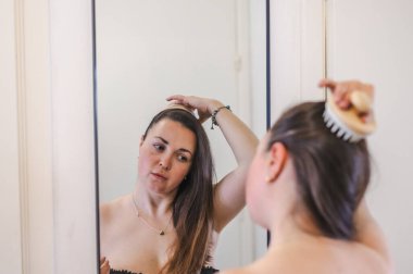 Bir kadın, günlük güzellik hizmetinin bir parçası olarak saçlarını nazikçe tarar. Sağlıklı, pürüzsüz ve bakımlı kilitleri teşvik eder..