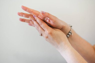 Hafif manikürlü, nemlendirici krem süren zarif kadın ellerinin yakın çekimi. Nazik el bakımı ve güzellik tedavisi.