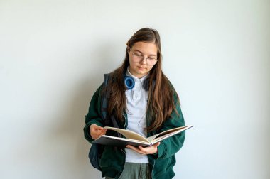 Elinde kitap tutan gülümseyen genç bir öğrenci, temiz beyaz bir arka plana karşı duruyor, okula ya da çalışmaya hazır..