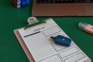 Yeşil bir arkaplanda düzenli olarak dizilmiş not defterleri, kalemler, keçeli kalemler ve makaslar da dahil olmak üzere okul malzemelerinden oluşan canlı bir çeşitlilik.